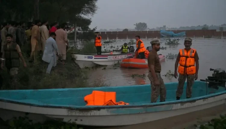 Pakistani army soldiers carrying civilians to safety during a dangerous flood rescue operation.