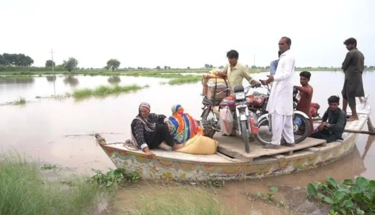 Aerial view of a flooded Punjabi village with people being rescued by boat.