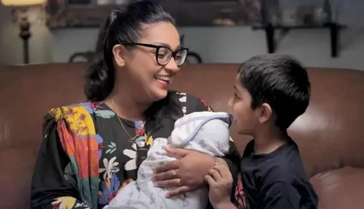 Uroosa Siddiqui holding her newborn son Farjad, smiling and sharing happiness with fans.