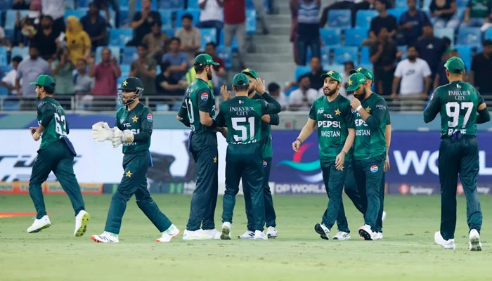 Pakistan cricketers celebrating a wicket against UAE in a night match at Dubai International Stadium.