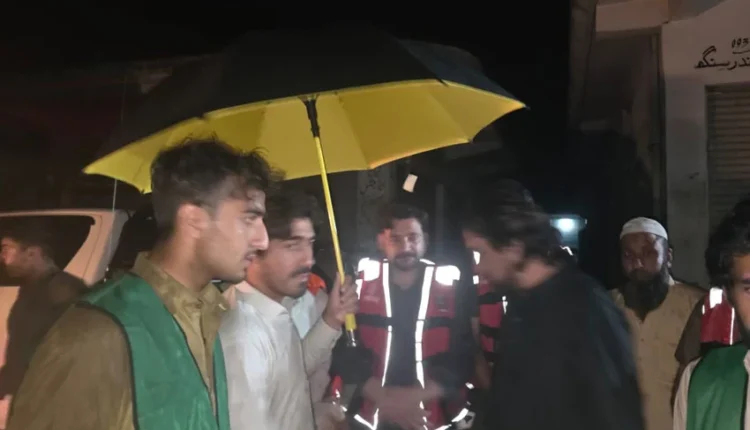 "A flooded street in Buner with residents evacuating and shops submerged"