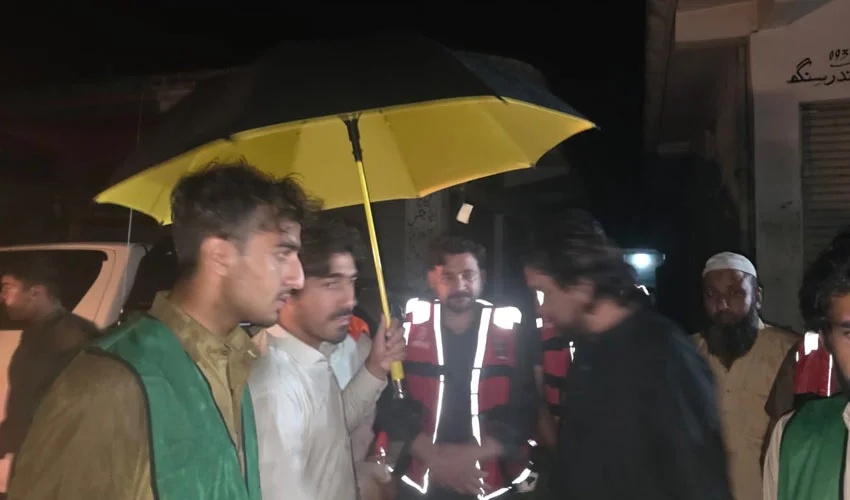 "A flooded street in Buner with residents evacuating and shops submerged"