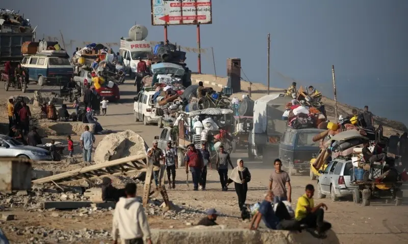 A long line of Palestinians fleeing Gaza City on foot and with donkey carts, carrying their belongings.