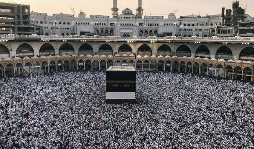 A diverse group of potential pilgrims discussing the new compassionate Hajj policy with a document.
