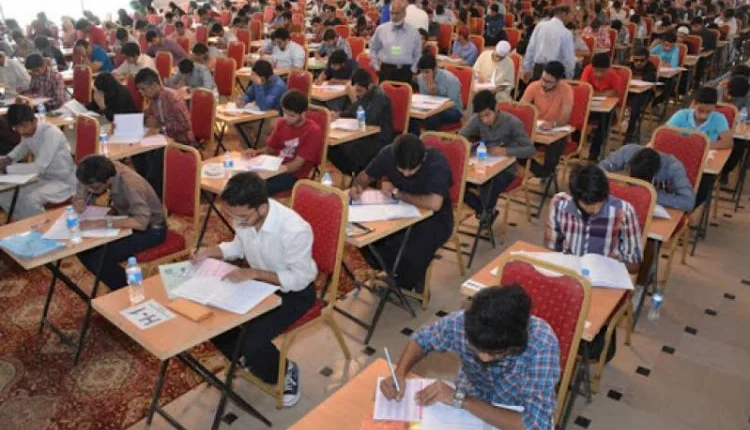 Students looking at a revised exam schedule on a notice board, following the MDCAT postponement