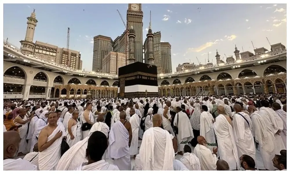 A diverse group of happy Pakistani pilgrims praying together at the holy Kaaba in Mecca.